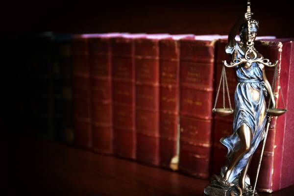 Statue of justice in front of law books.