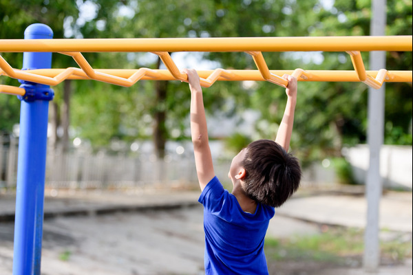 Young boy on monkey bars at a playground.
