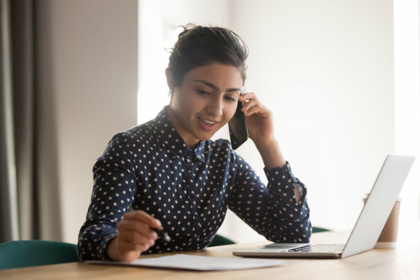 A woman talks on the phone and takes notes