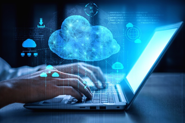 The concept of cloud computing displayed with a person typing on a laptop behind the digital cloud connected to various data points.