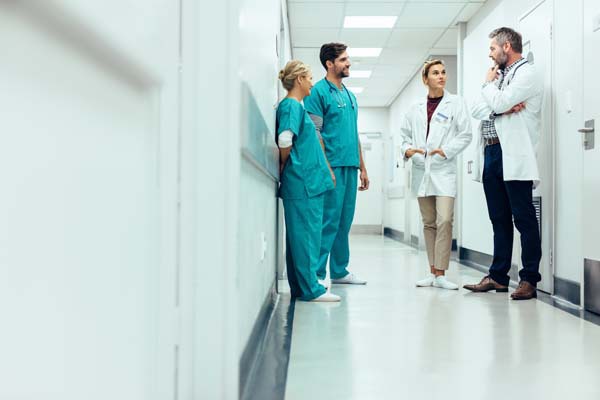 A group of doctors and nurses talking to each other in a hospital hallway.