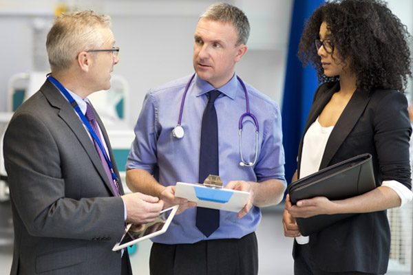 Three health workers talk about a patient.