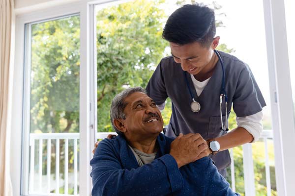 A nurse smiling and providing support to an older patient.