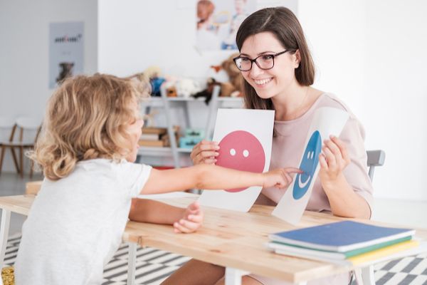 A woman holds two pieces of paper and a child points at one