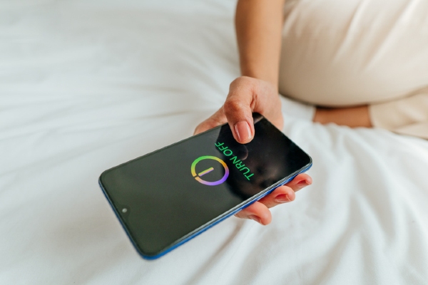A hand holding a mobile phone that is being turned off.