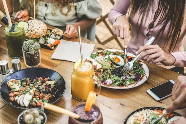 A group of people sit at a table and eat salads.