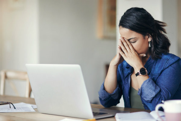 30-something woman sitting at her laptop, obviously stressed.