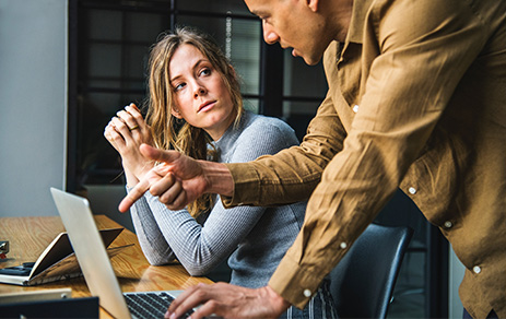 man and women talking at desk with laptop