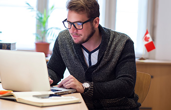 Canadian man in glasses exploring financial options on laptop