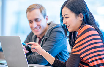 man and women smiling and chatting in front of a laptop