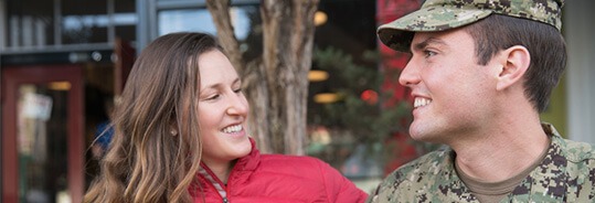 Servicemember in uniform smiling next to a woman