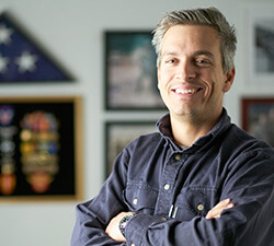 man standing in front of wall with military plaques